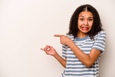 Beyaz arka planda izole edilmiş genç Afrikalı Amerikalı kadın işaret parmağıyla fotokopi alanını işaret ederek şok oldu..