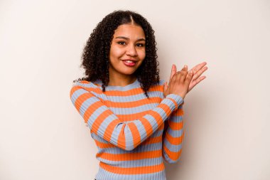 Beyaz arka planda izole edilmiş genç Afrikalı Amerikalı kadın enerjik ve rahat hissediyor, ellerini ovuşturuyor..