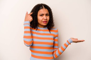 Beyaz arka planda izole edilmiş genç Afrikalı Amerikalı kadın elinde bir ürün tutuyor ve.