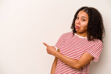 Beyaz arka planda izole edilmiş genç bir Afrikalı Amerikalı kadın gülümsüyor ve boş alanda bir şeyler gösteriyor..