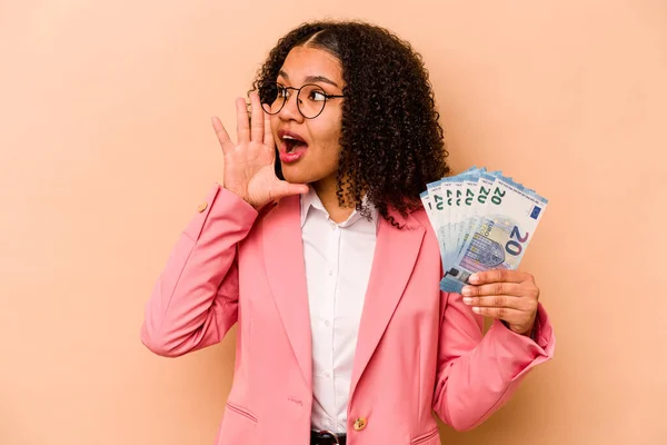若いアフリカ系アメリカ人のビジネス女性は ベージュの背景の叫びに隔離された紙幣を保持し 口を開けた近くに手のひらを保持 — ストック写真