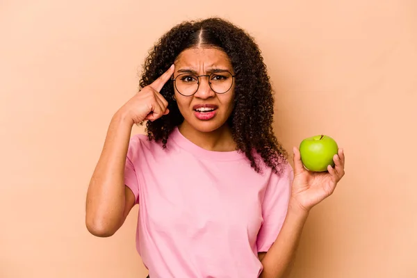 Ung Afroamerikansk Kvinna Håller Ett Äpple Isolerat Beige Bakgrund Visar — Stockfoto