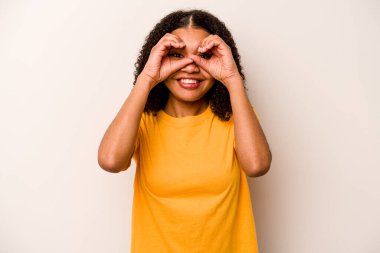 Beyaz arka planda izole edilmiş genç Afrikalı Amerikalı kadın gözlerinde iyi işareti gösteriyor.