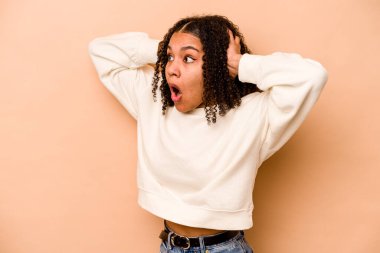 Genç Afrikalı Amerikalı kadın bej arka planda izole edilmiş bağırıyor, çok heyecanlı, tutkulu, bir şeyden memnun..