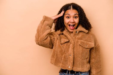 Genç Afrikalı Amerikalı kadın bej arka planda izole edilmiş yüksek sesle bağırıyor, gözleri açık ve elleri gergin tutuyor..