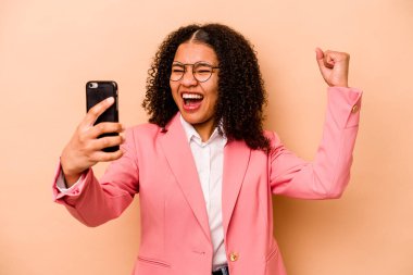 Bej arka planda cep telefonu tutan genç Afrikalı Amerikalı iş kadını