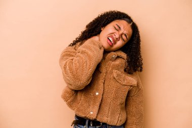 Genç Afrikalı Amerikalı kadın bej arka planda izole edilmiş. Oturmalı yaşam tarzından dolayı boyun ağrısı çekiyor..