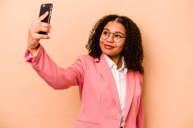 Bej arka planda cep telefonu tutan genç Afrikalı Amerikalı iş kadını