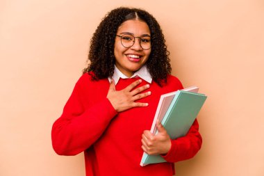 Genç Afrikalı Amerikalı kadın, bej arka planda izole edilmiş. Yüksek sesle kahkahalar atıyor..