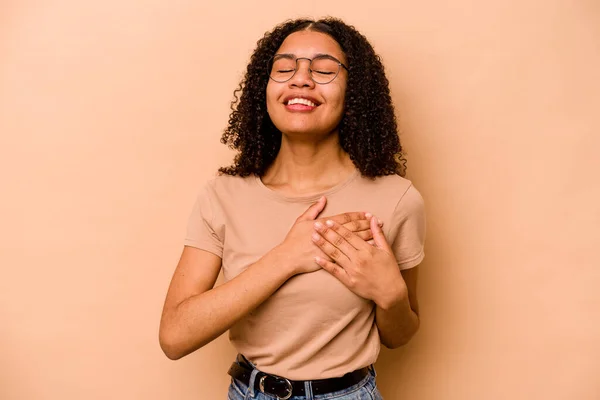 Молодая Африканская Американка Изолирована Бежевом Фоне Смеясь Держа Руки Сердце — стоковое фото