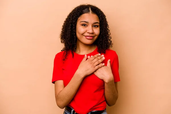 在米色背景上被隔离的年轻的非洲裔美国妇女有友好的表达方式 将手掌压在胸前 爱情的概念 — 图库照片
