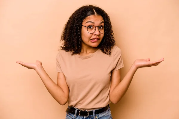 Joven Mujer Afroamericana Aislada Sobre Fondo Beige Confundida Dudosa Hombros —  Fotos de Stock