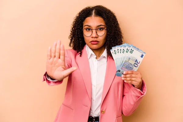 Mladá Afroameričanka Drží Bankovky Izolované Béžovém Pozadí Nataženou Rukou Ukazující — Stock fotografie