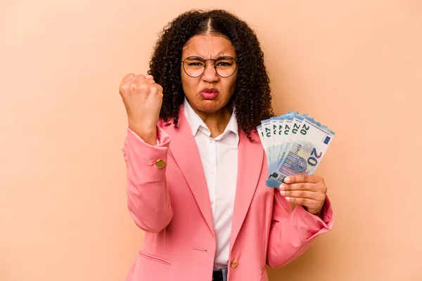 若いアフリカ系アメリカ人のビジネス女性は カメラに拳を示すベージュの背景に隔離された紙幣を保持します 積極的な表情 — ストック写真