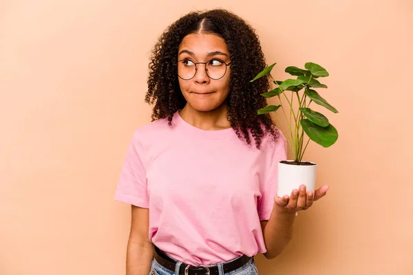 Young African American Woman Holding Plant Isolated Beige Background Confused — 스톡 사진