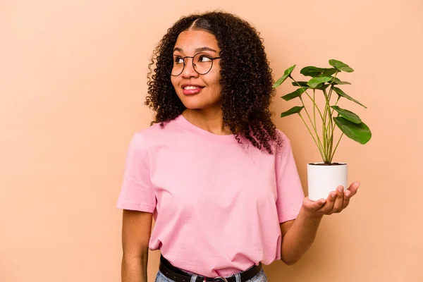 Young African American Woman Holding Plant Isolated Beige Background Looks — 스톡 사진
