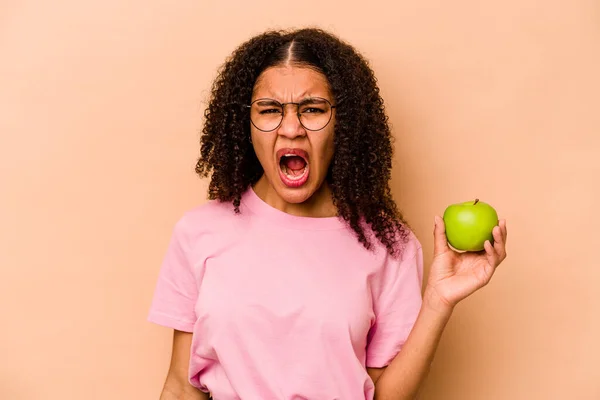 Ung Afroamerikansk Kvinna Håller Ett Äpple Isolerat Beige Bakgrund Skriker — Stockfoto