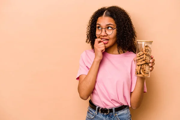 Young African American Woman Holding Cookies Jar Isolated Beige Background — Stockfoto