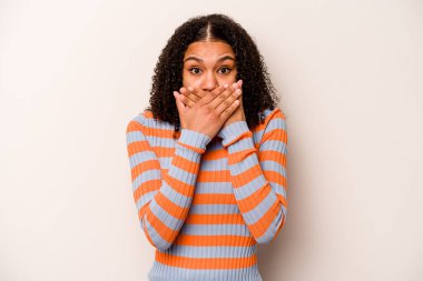Beyaz arka planda izole edilmiş genç Afrikalı Amerikalı kadın elleriyle ağzını kapatırken şok oldu..