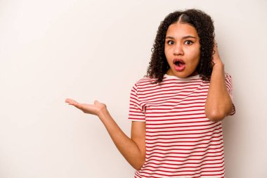 Beyaz arka planda izole edilmiş genç Afrikalı Amerikalı kadın, avuç içlerindeki fotokopi alanını tutmaktan etkilenmiş..