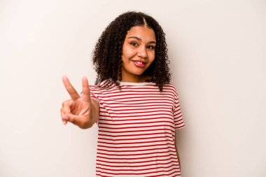 Beyaz arka planda izole edilmiş genç Afrikalı Amerikalı kadın zafer işareti gösteriyor ve gülümsüyor..