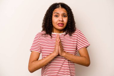 Beyaz arka planda izole edilmiş genç bir Afrikalı Amerikalı kadın el ele dua ediyor, kendine güveniyor..