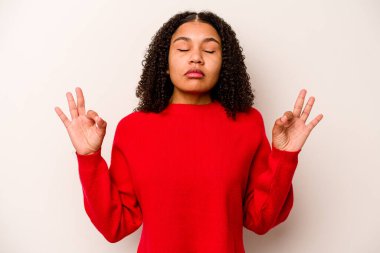Beyaz arka planda izole edilmiş genç Afrikalı Amerikalı kadın yoğun bir günün ardından dinleniyor, yoga yapıyor..