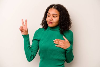 Genç Afrikalı Amerikalı kadın beyaz arka planda izole edilmiş yemin ediyor, elini göğsüne koyuyor..