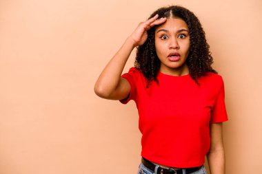 Genç Afrikalı Amerikalı kadın bej arka planda izole edilmiş yüksek sesle bağırıyor, gözleri açık ve elleri gergin tutuyor..