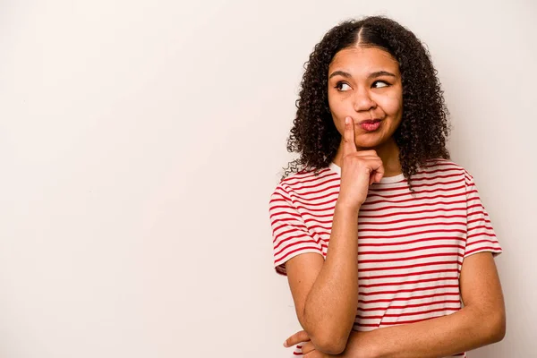 アフリカ系アメリカ人の若い女性は 疑いと懐疑的な表情で横に見える白い背景に隔離されています — ストック写真
