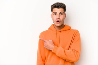 Beyaz arka planda izole edilmiş genç beyaz adam yan tarafı işaret ediyor