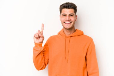 Beyaz arka planda izole edilmiş beyaz tenli genç bir adam bir numarayı parmağıyla gösteriyor..