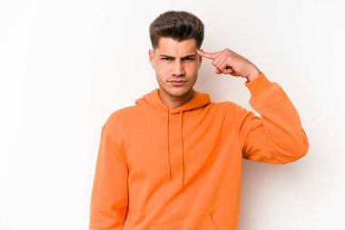 Beyaz arka planda izole edilmiş genç beyaz bir adam şakağı parmağıyla işaret ediyor, düşünüyor ve bir göreve odaklanıyor..