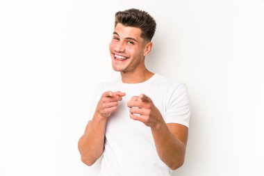 Beyaz arka planda izole edilmiş genç beyaz adam parmaklarıyla ön tarafı işaret ediyor..
