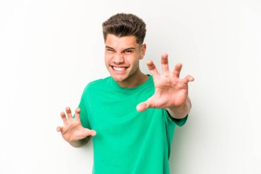 Beyaz arka planda izole edilmiş genç beyaz bir adam pençelerini kedi taklidi yaparken gösteriyor, agresif bir hareket..