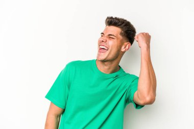 Beyaz arka planda izole edilmiş genç beyaz bir adam zaferi, tutkuyu ve coşkuyu kutluyor, mutlu bir ifade..