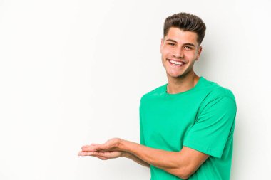 Beyaz arka planda izole edilmiş beyaz tenli genç bir adam palmiyesinde bir kopya alanı tutuyor..