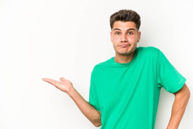 Beyaz arka planda izole edilmiş genç beyaz bir adam bir palmiye üzerinde fotokopi alanı gösteriyor ve belinde başka bir el tutuyor..