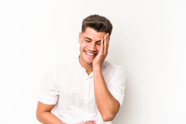 Beyaz arka planda izole genç beyaz adam mutlu bir şekilde gülüyor ve ellerini karnının üstünde tutarak eğleniyor..