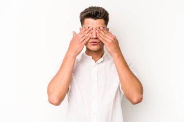 Beyaz arka planda izole edilmiş genç beyaz bir adam elleriyle gözlerini kapatmaktan korkuyor..