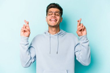 Kafkasyalı genç adam mavi arka planda izole edilmiş şans dilemek için şans diliyor.