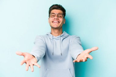 Mavi arka planda izole edilmiş beyaz bir genç hoş bir yüz ifadesi sergiliyor..