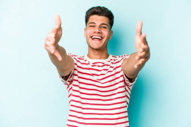 Mavi arka planda izole edilmiş genç beyaz adam kameraya sarıldığı için kendinden emin hissediyor..