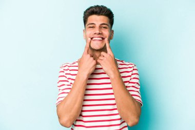 Kafkasyalı genç adam mavi arka planda izole edilmiş iki seçenek arasında şüphe duyuyor.