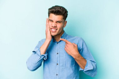 Mavi arka planda izole genç beyaz adam güçlü bir diş ağrısı, azıdişi ağrısı var..