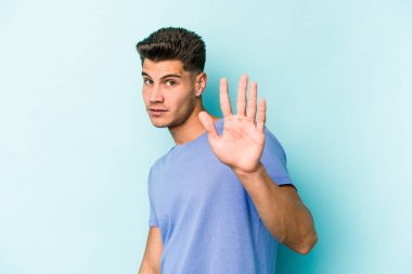 Mavi arka planda izole edilmiş genç beyaz adam tiksinti belirtisi gösteren birini reddediyor..