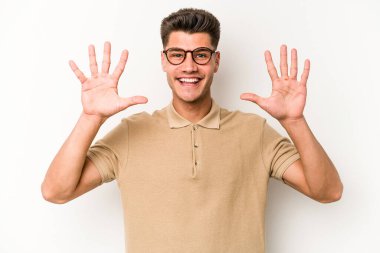 Beyaz arka planda izole edilmiş beyaz tenli genç adam on numarayı elleriyle gösteriyor..