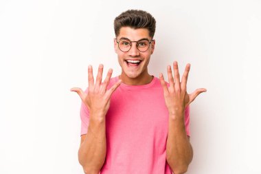 Beyaz arka planda izole edilmiş beyaz tenli genç adam on numarayı elleriyle gösteriyor..