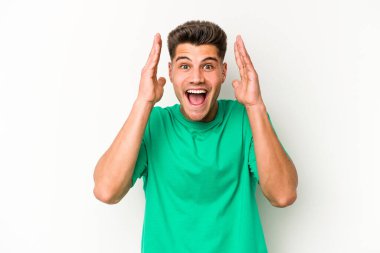 Beyaz arka planda izole genç beyaz adam hoş bir sürpriz alıyor, heyecanlı ve el kaldırıyor..