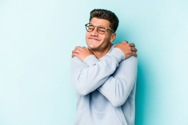 Kafkasyalı genç adam mavi arka planda izole edilmiş, güler yüzlü ve mutlu..